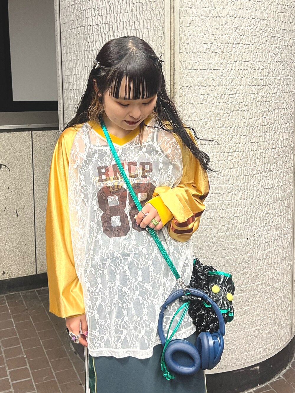 グリーン系のスカート、ブラック系のショルダーバッグ、イエロー系のTシャツ/カットソーを着用したレディースの冬コーディネートの4枚目の写真