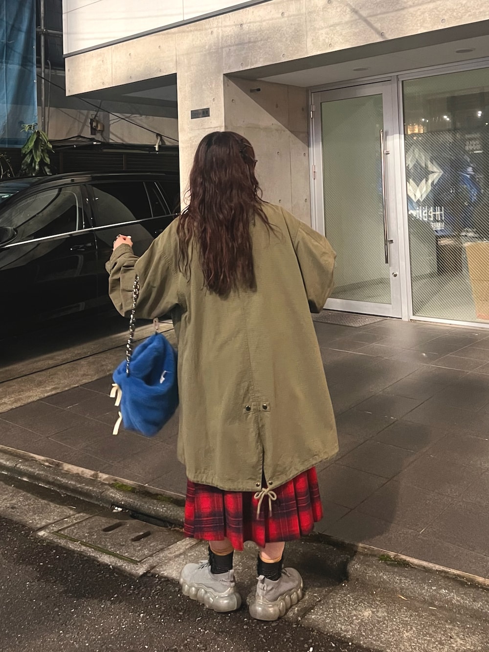 レッド系のスウェット、グリーン系のモッズコート、レッド系のスカートを着用したレディースの秋コーディネートの2枚目の写真