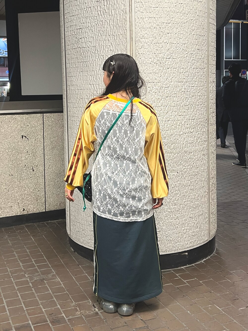 グリーン系のスカート、ブラック系のショルダーバッグ、イエロー系のTシャツ/カットソーを着用したレディースの冬コーディネートの3枚目の写真