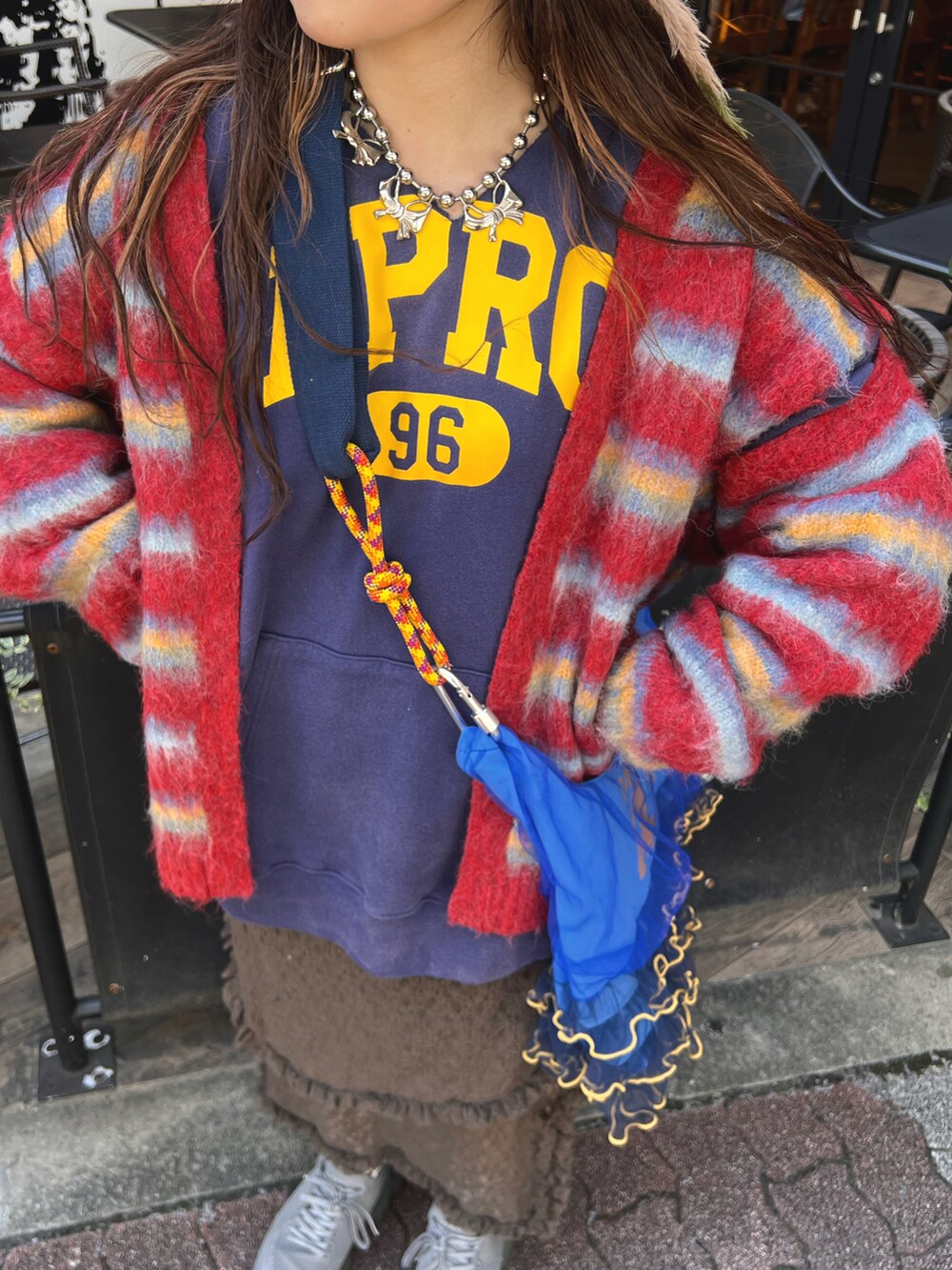 ブラック系のパーカー、レッド系のカーディガン/ボレロ、ブラウン系のスカートを着用したレディースの秋コーディネートの4枚目の写真