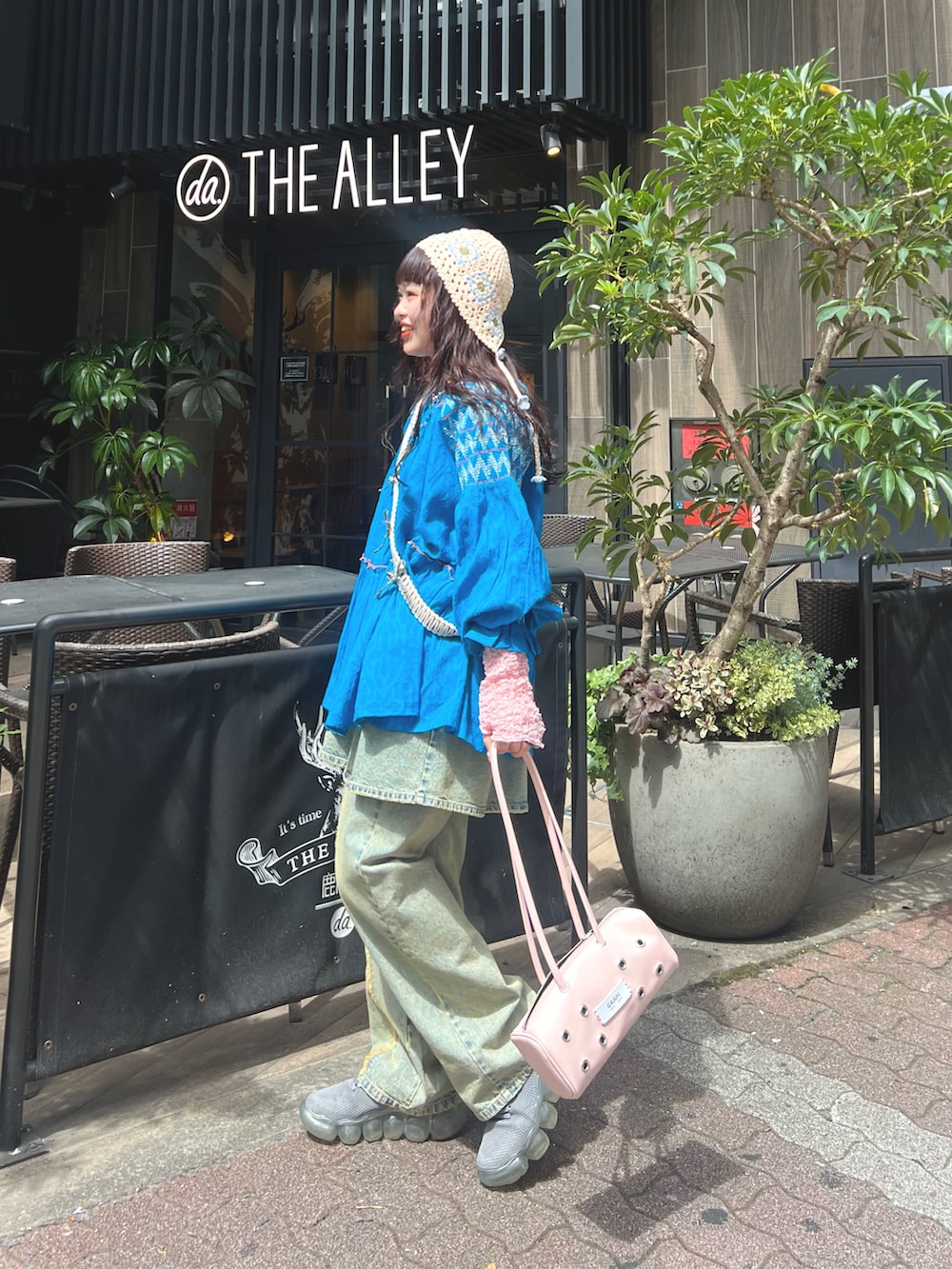 ブルー系のトップス、ブルー系のデニムパンツ、ピンク系のバッグを着用したレディースの春コーディネートの2枚目の写真