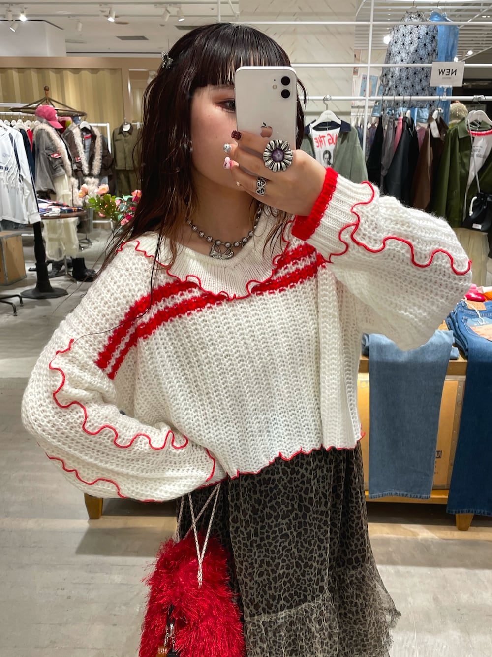 ホワイト系のニット/セーター、ベージュ系のスカート、レッド系のショルダーバッグを着用したレディースの秋コーディネートの2枚目の写真