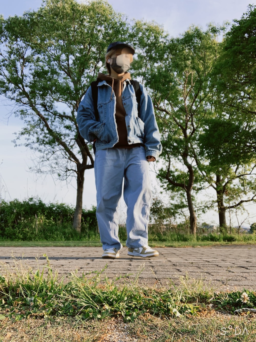 ブルー系のデニムジャケット、ブラウン系のパーカー、ブルー系のデニムパンツを着用したレディースの春コーディネートの3枚目の写真