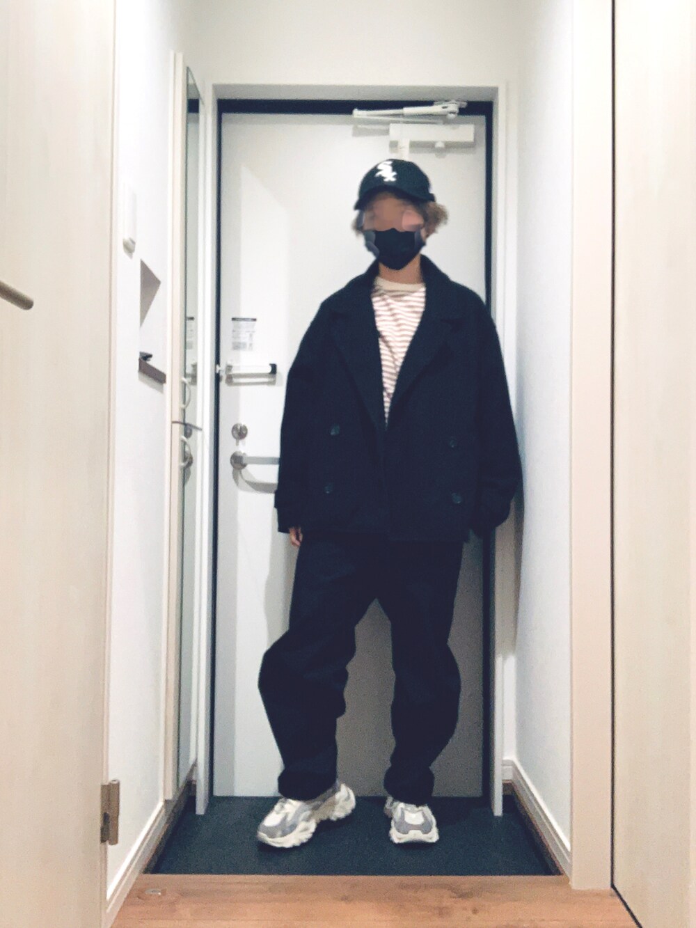 ブラック系のトレンチコート、ブラック系のパンツ、グレー系のスニーカーを着用したレディースの冬コーディネートの2枚目の写真