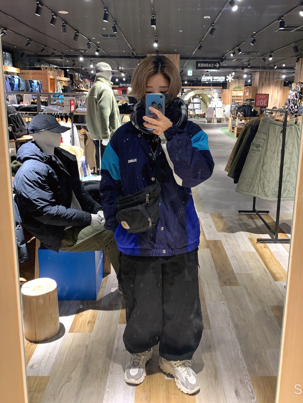 ブラック系のカーゴパンツ、グレー系のスニーカー、ブルー系のナイロンジャケットを着用したレディースの冬コーディネートの2枚目の写真