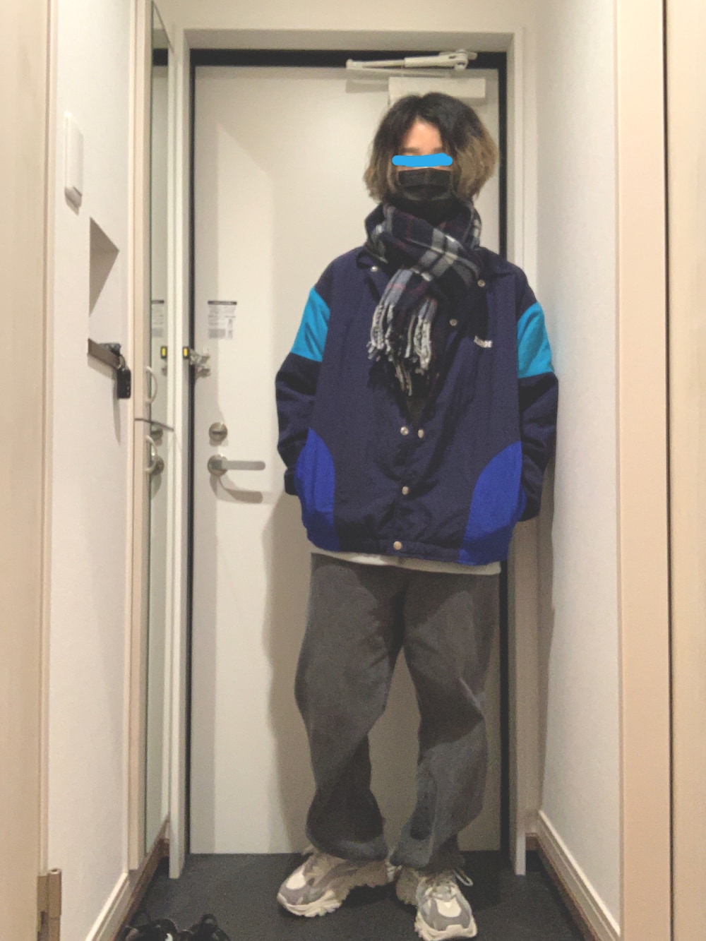 ブルー系のナイロンジャケット、ブラック系のデニムパンツ、グレー系のスニーカーを着用したレディースの冬コーディネートの2枚目の写真