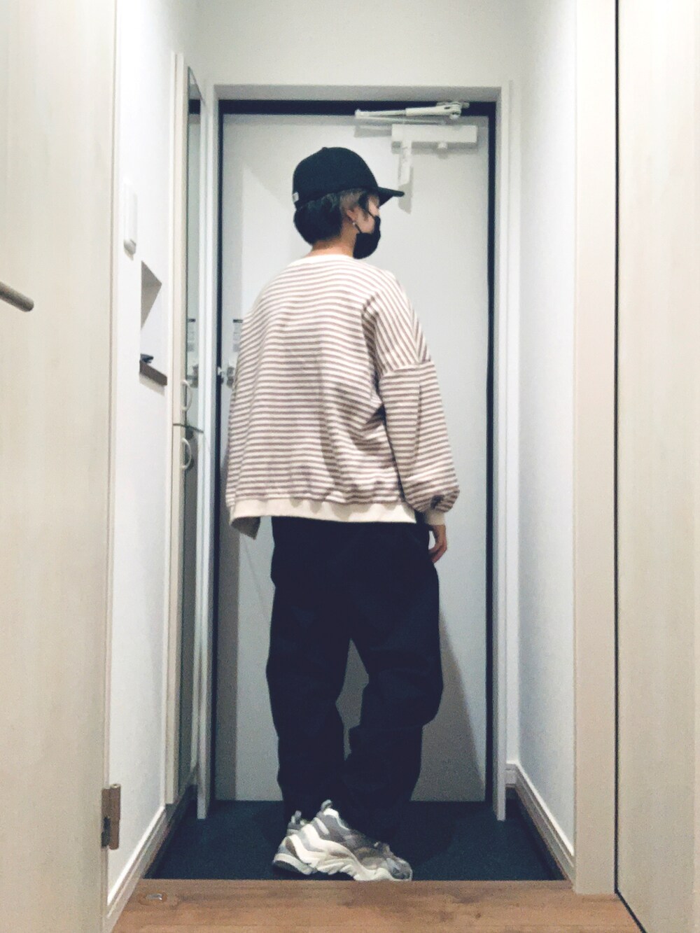 ブラック系のトレンチコート、ブラック系のパンツ、グレー系のスニーカーを着用したレディースの冬コーディネートの3枚目の写真