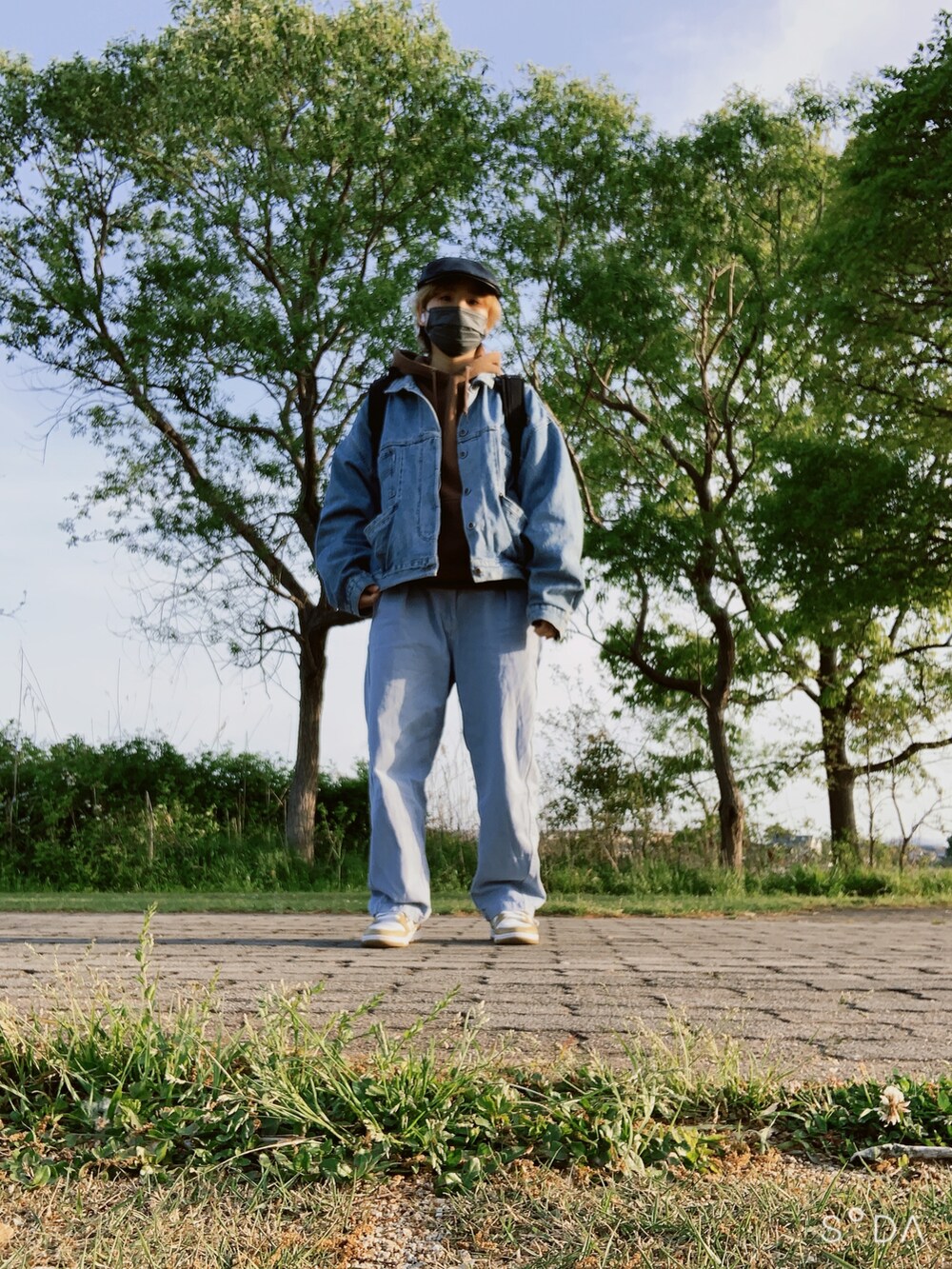 ブルー系のデニムジャケット、ブラウン系のパーカー、ブルー系のデニムパンツを着用したレディースの春コーディネートの2枚目の写真