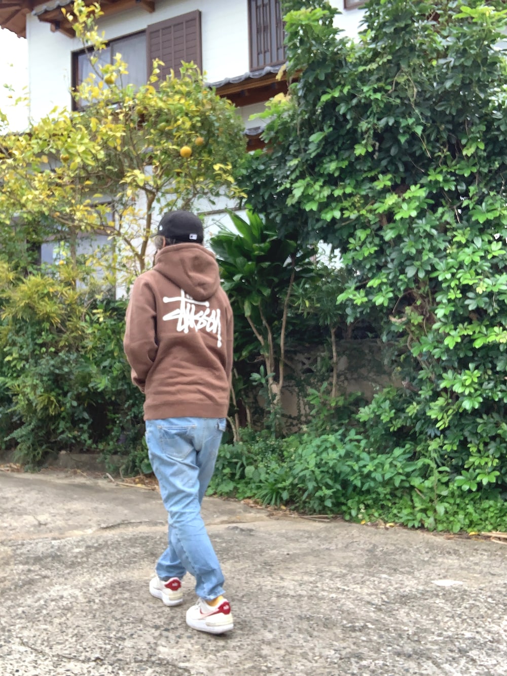 ブラウン系のパーカー、ブルー系のデニムパンツ、ホワイト系のスニーカーを着用したレディースの冬コーディネートの2枚目の写真