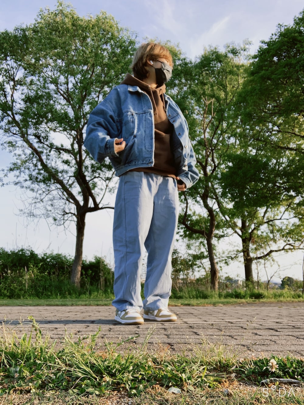 ブルー系のデニムジャケット、ブラウン系のパーカー、ブルー系のデニムパンツを着用したレディースの春コーディネートの4枚目の写真