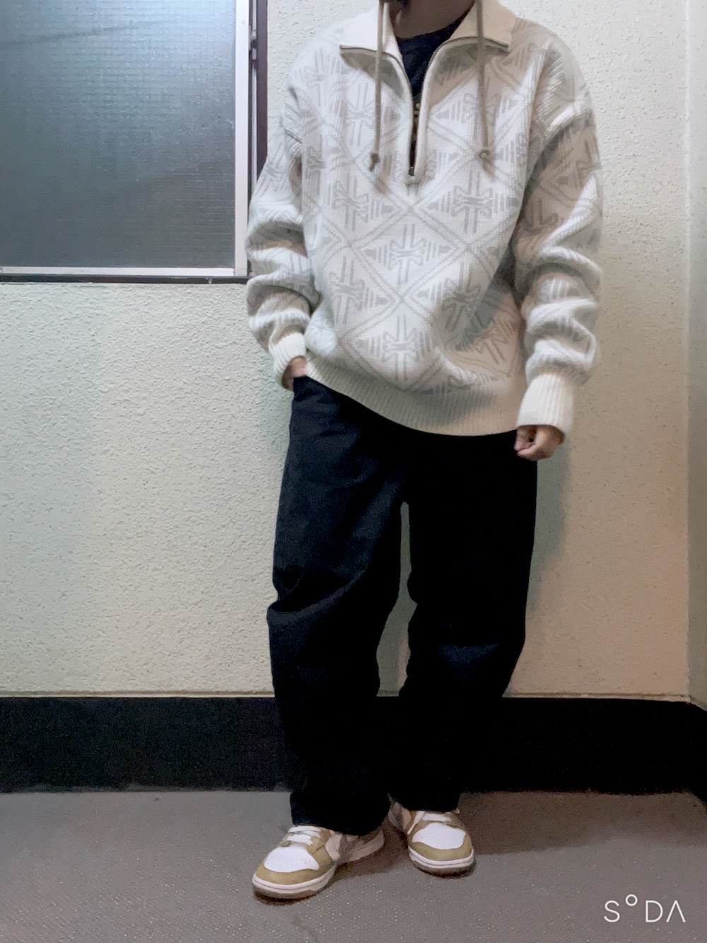 ブラック系のチノパンツ、イエロー系のスニーカー、ホワイト系のニット/セーターを着用したレディースの冬コーディネートの2枚目の写真