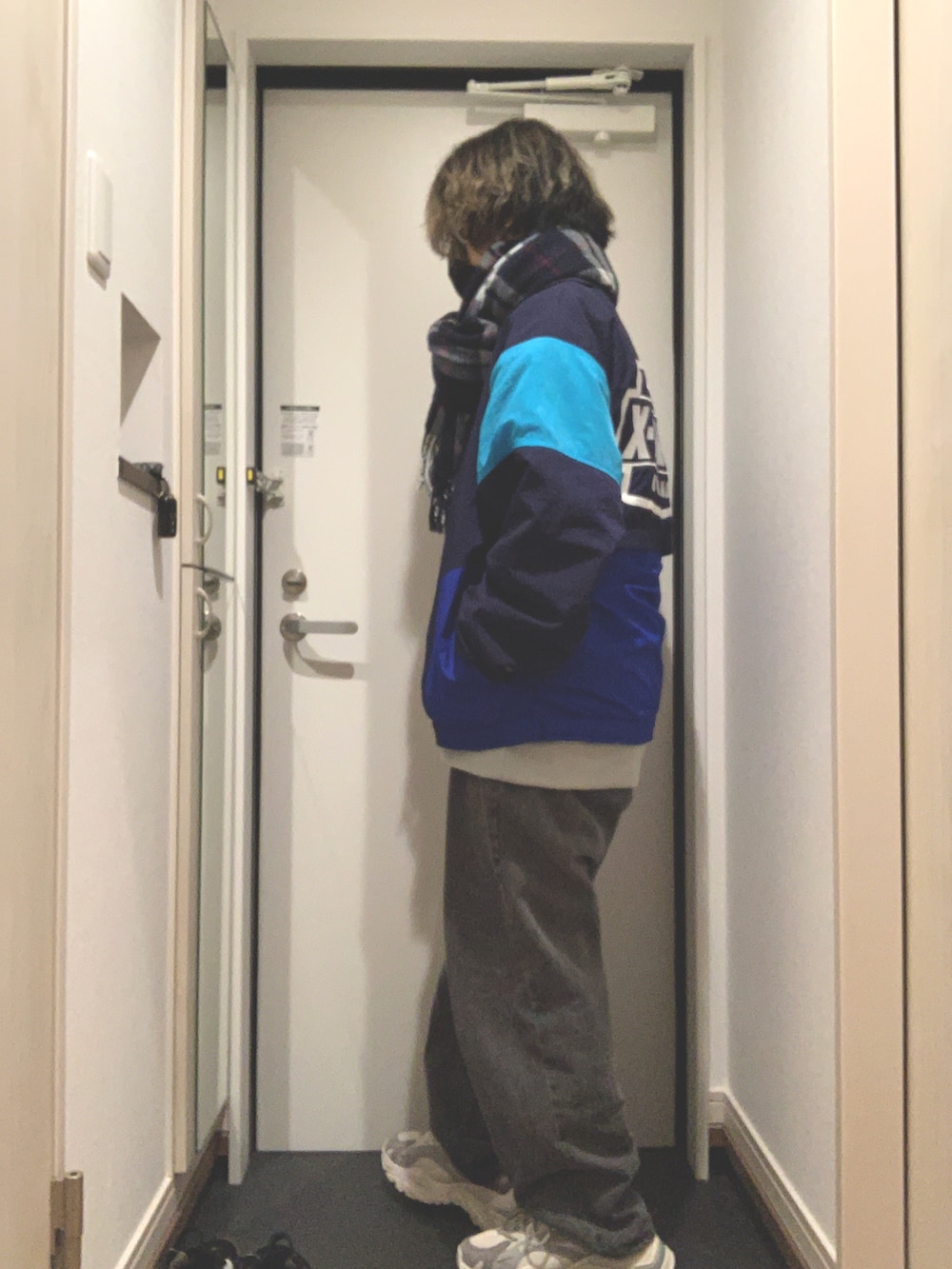 ブルー系のナイロンジャケット、ブラック系のデニムパンツ、グレー系のスニーカーを着用したレディースの冬コーディネートの3枚目の写真