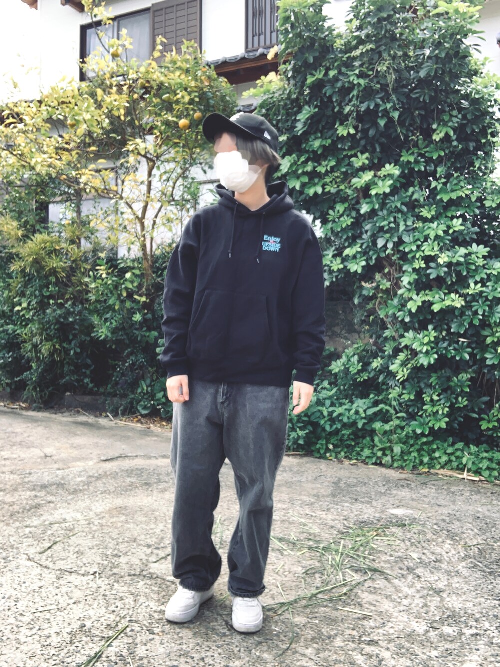 ブラック系のパーカー、ブラック系のデニムパンツ、ホワイト系のスニーカーを着用したレディースの冬コーディネートの2枚目の写真