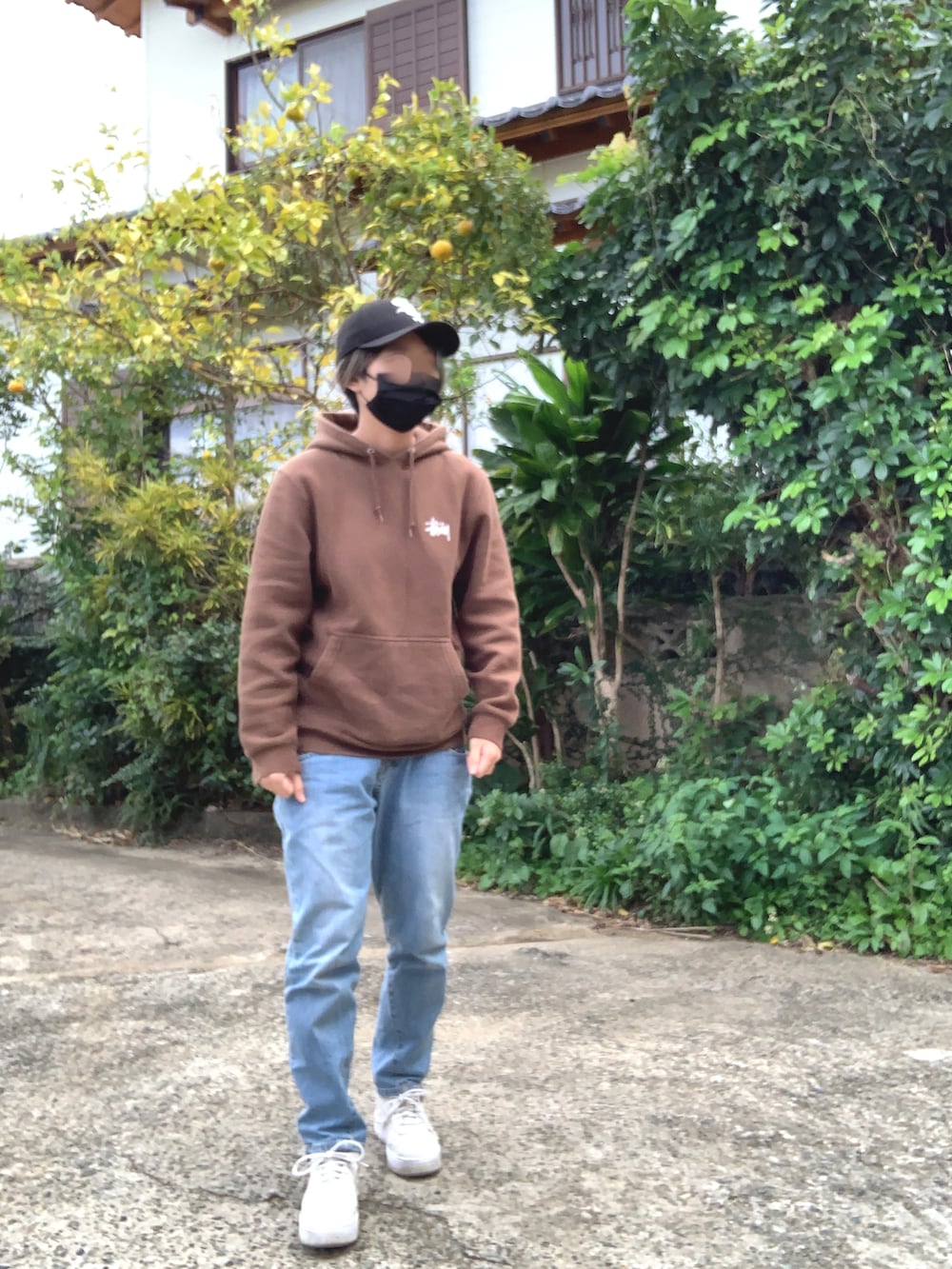 ブラウン系のパーカー、ブルー系のデニムパンツ、ホワイト系のスニーカーを着用したレディースの冬コーディネートの3枚目の写真