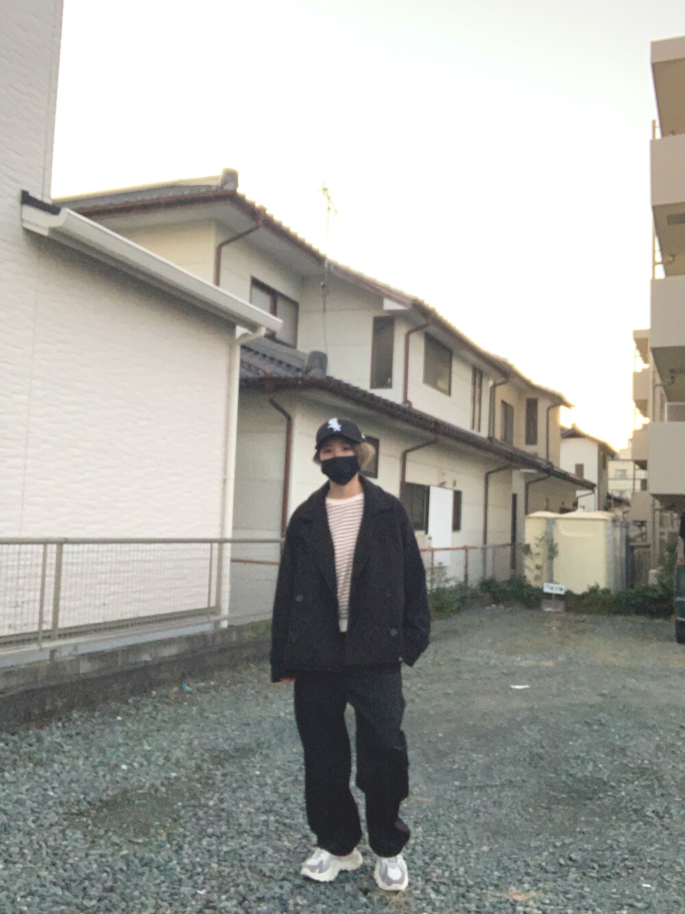 ブラック系のトレンチコート、ブラック系のパンツ、グレー系のスニーカーを着用したレディースの冬コーディネートの4枚目の写真