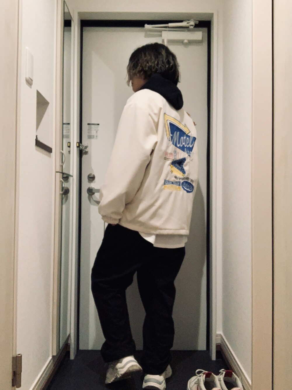 ブラック系のパーカー、ブラック系のパンツ、グレー系のスニーカーを着用したレディースの冬コーディネートの3枚目の写真