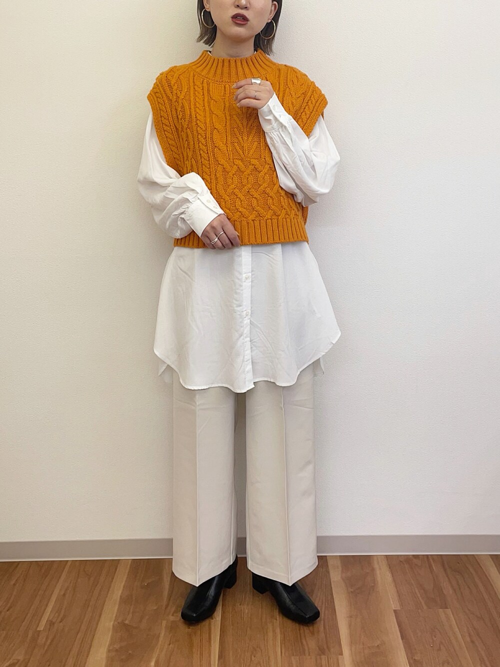 ブラック系のブーツ、ホワイト系のその他パンツ、オレンジ系のベストを着用したレディースの冬コーディネートの2枚目の写真