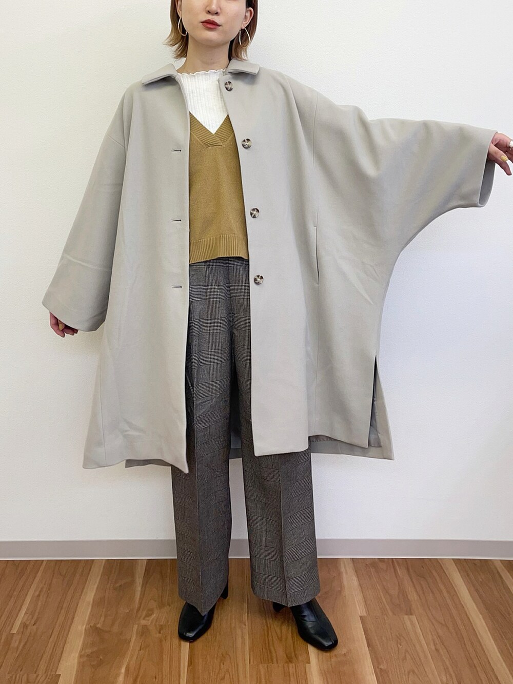 ブラック系のブーツ、グレー系のその他パンツ、ホワイト系のポンチョを着用したレディースの冬コーディネートの2枚目の写真