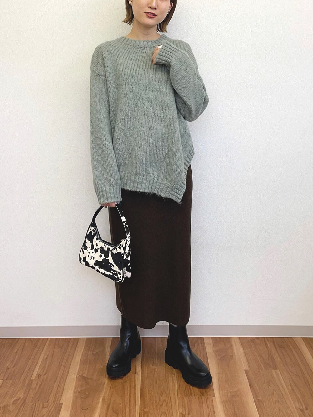 ブラック系のハンドバッグ、グリーン系のニット/セーター、ブラック系のブーツを着用したレディースの冬コーディネートの2枚目の写真