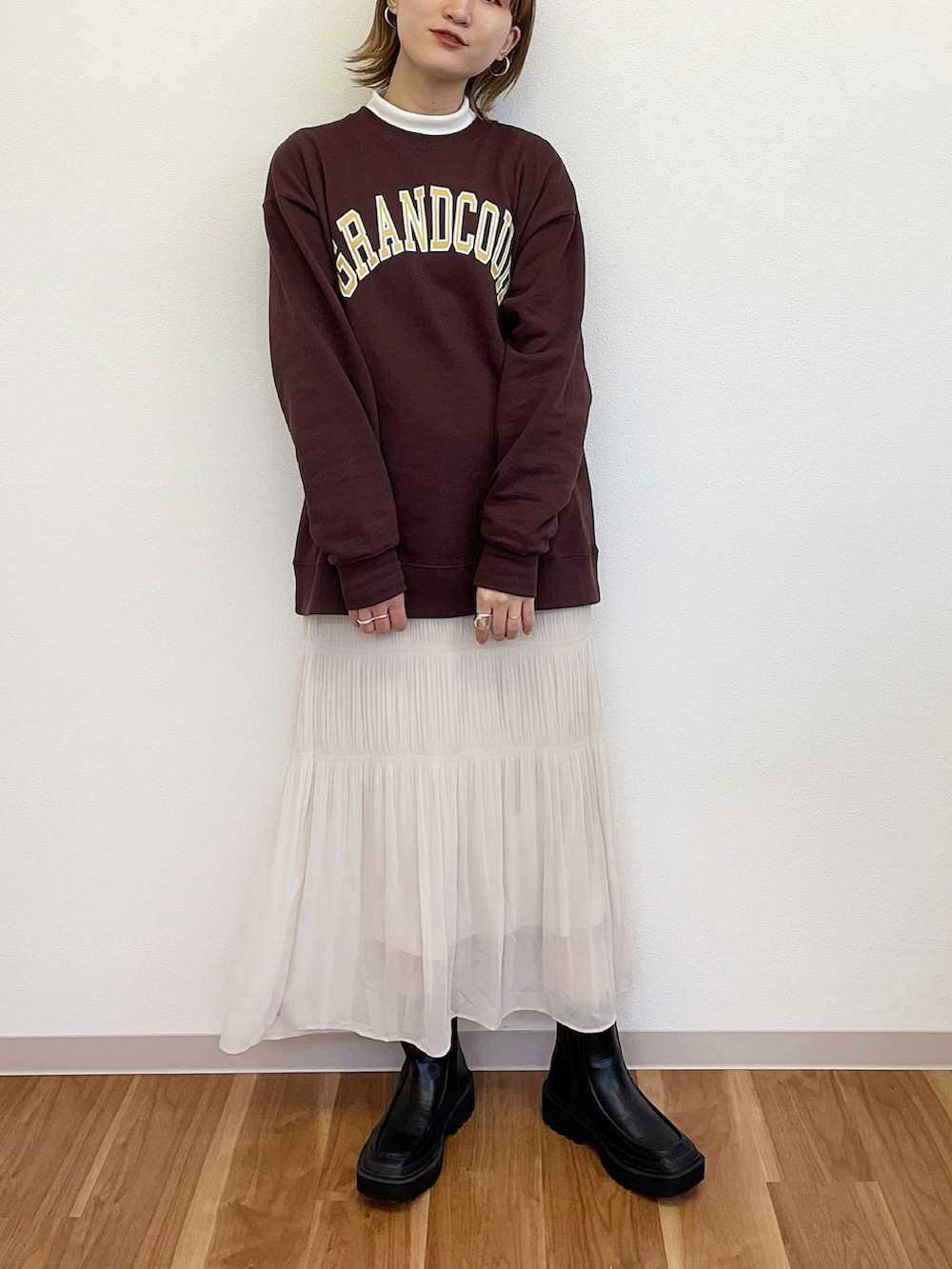 ホワイト系のスカート、ブラウン系のスウェット、ブラック系のブーツを着用したレディースの冬コーディネートの2枚目の写真