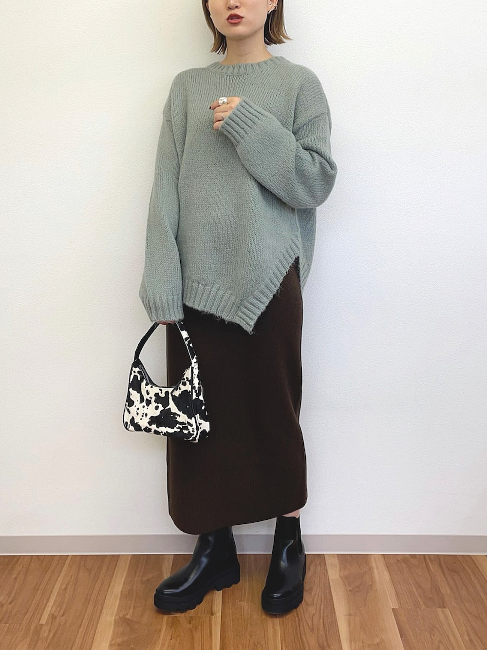 ブラック系のハンドバッグ、グリーン系のニット/セーター、ブラック系のブーツを着用したレディースの冬コーディネートの3枚目の写真