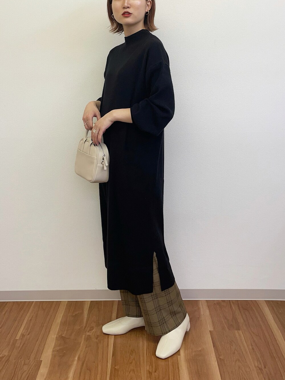 ホワイト系のボストンバッグ、ブラック系のワンピース、ホワイト系のブーツを着用したレディースの秋コーディネートの2枚目の写真