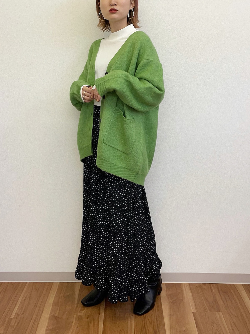 グリーン系のカーディガン/ボレロ、ブラック系のスカート、ブラック系のブーツを着用したレディースの冬コーディネートの2枚目の写真