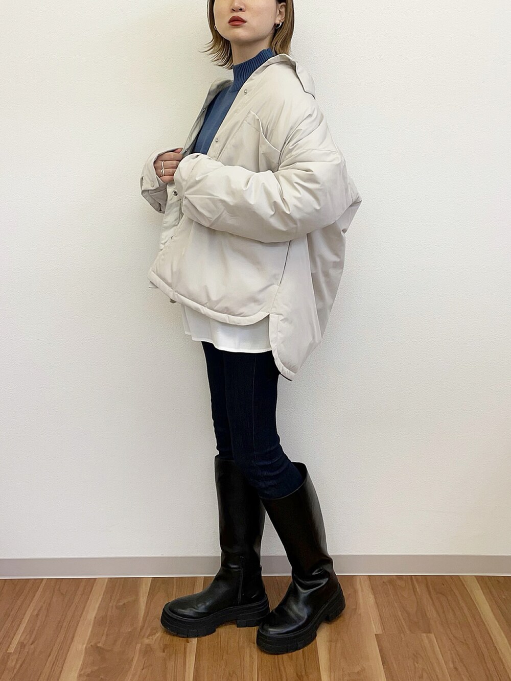 ブラック系のブーツ、ブラック系のデニムパンツ、ブルー系のニット/セーターを着用したレディースの冬コーディネートの2枚目の写真