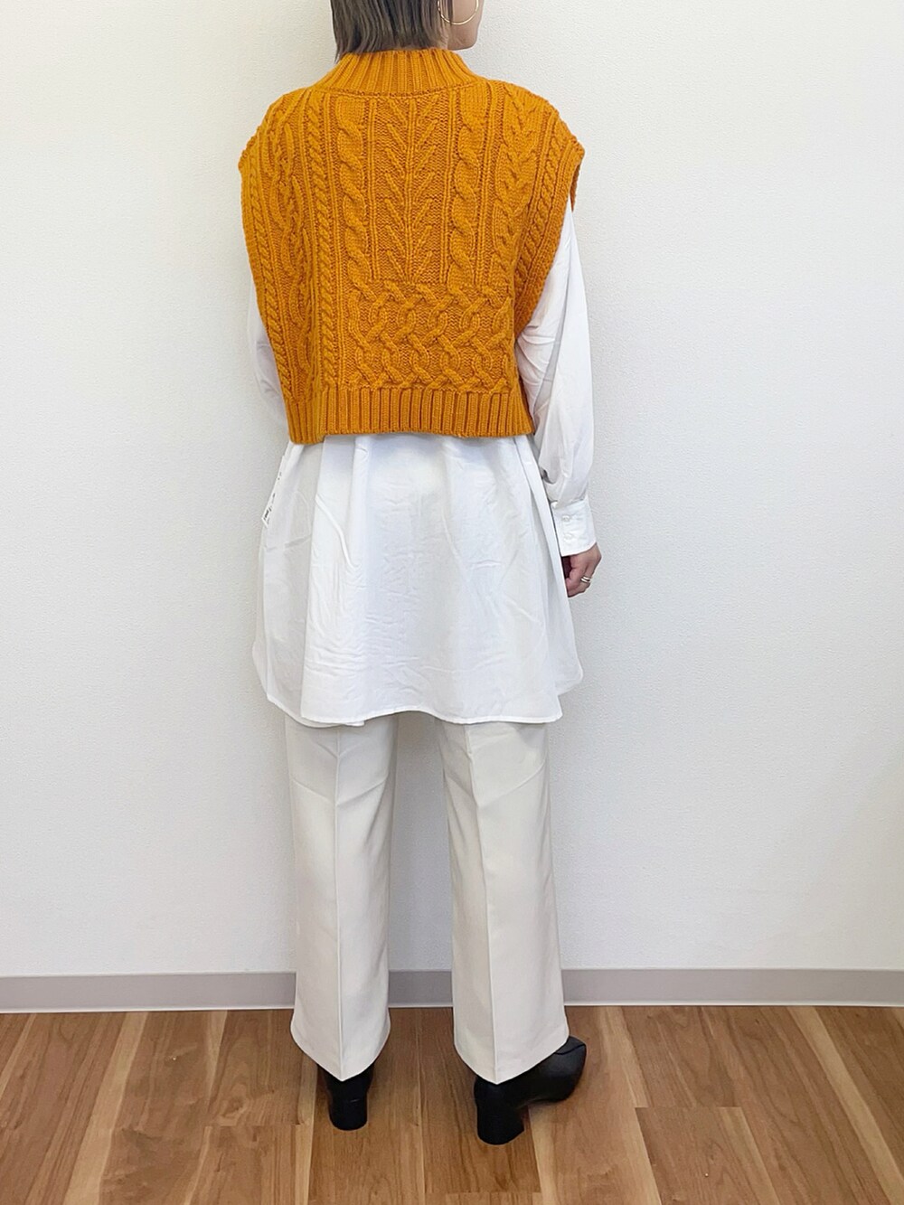 ブラック系のブーツ、ホワイト系のその他パンツ、オレンジ系のベストを着用したレディースの冬コーディネートの3枚目の写真