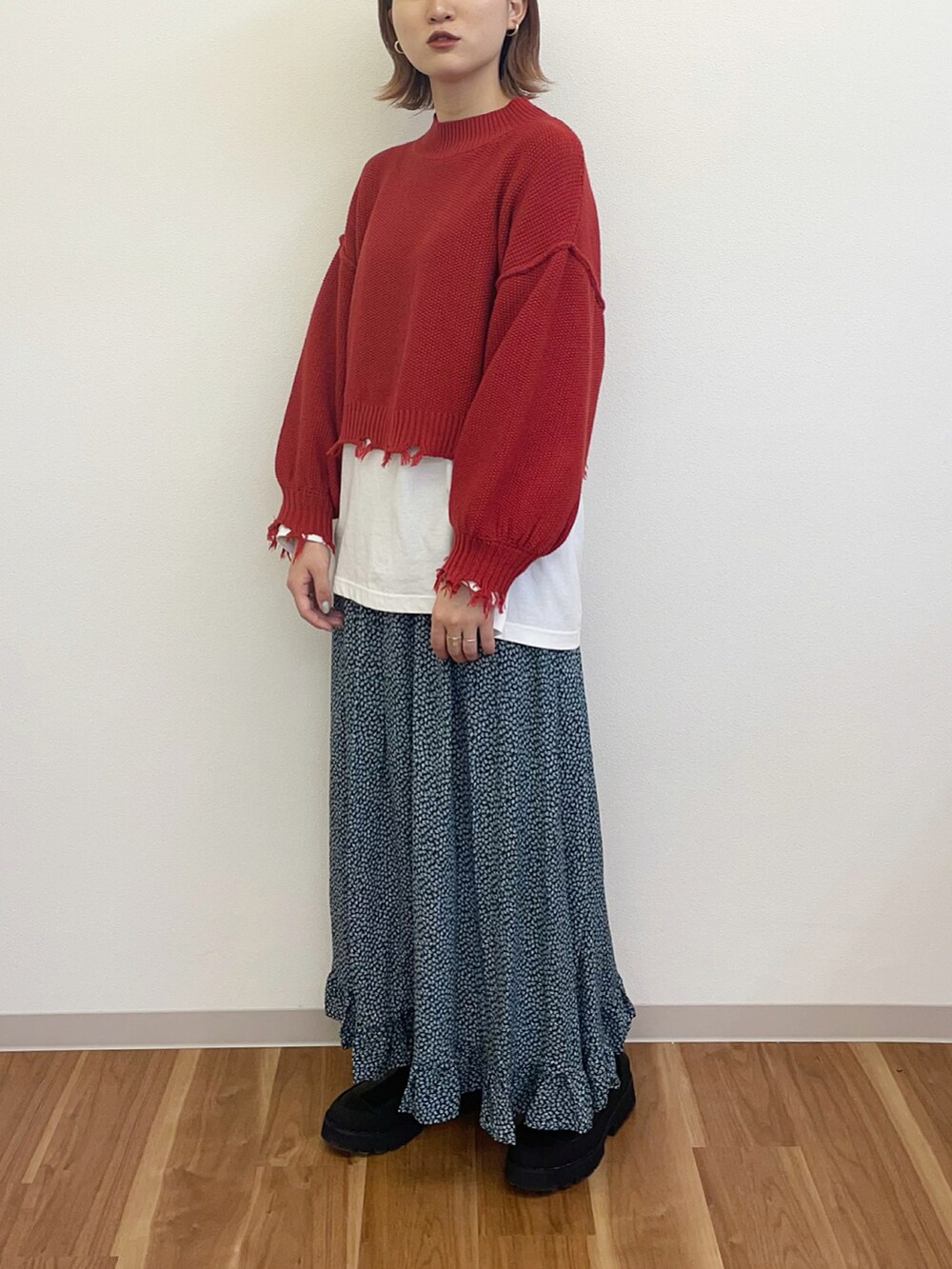 レッド系のニット/セーター、グリーン系のスカート、ブラック系のブーツを着用したレディースの冬コーディネートの3枚目の写真