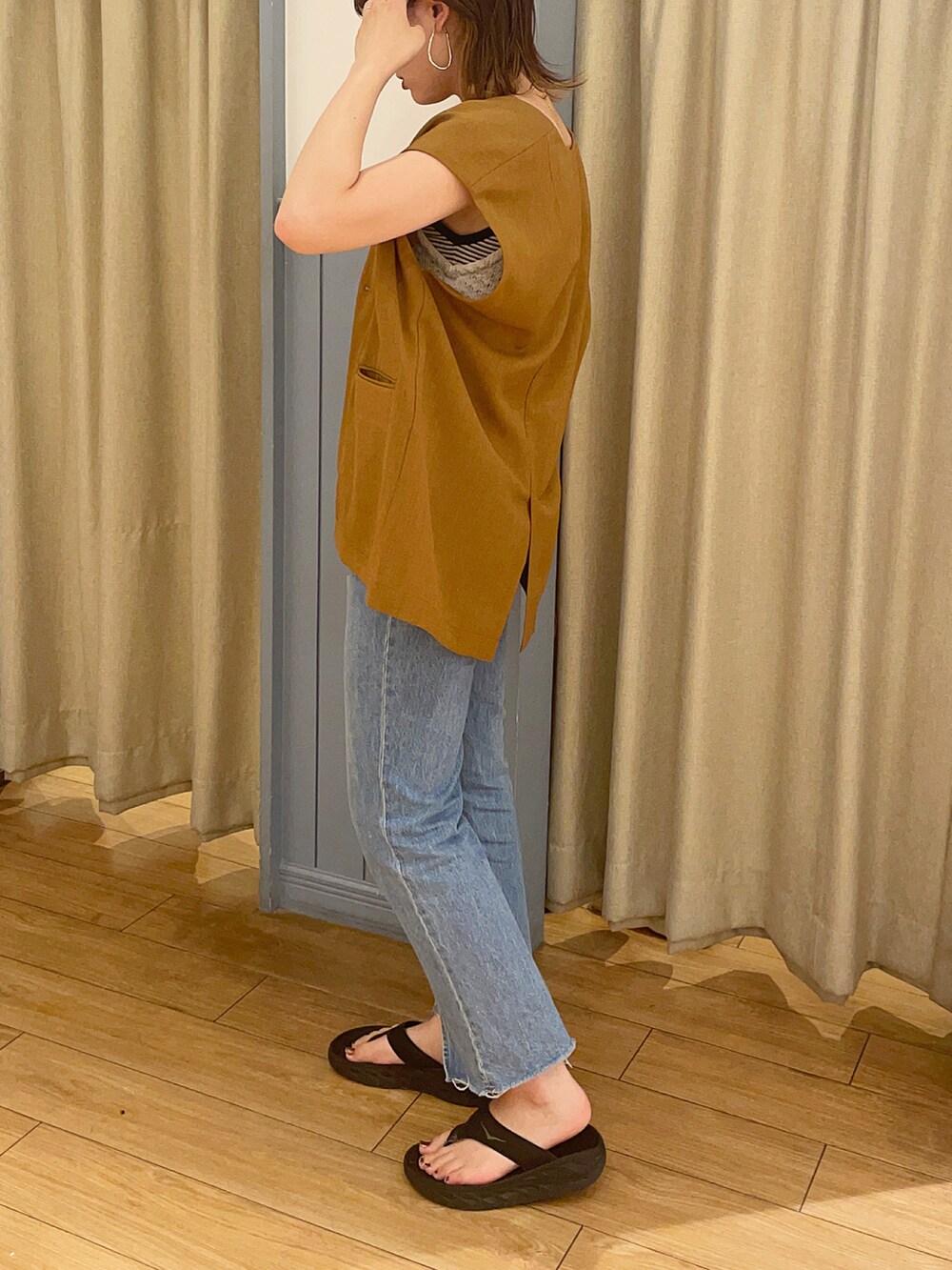 ブルー系のデニムパンツ、ブラック系のサンダル、ブラウン系のジャケット/アウターを着用したレディースの夏コーディネートの2枚目の写真