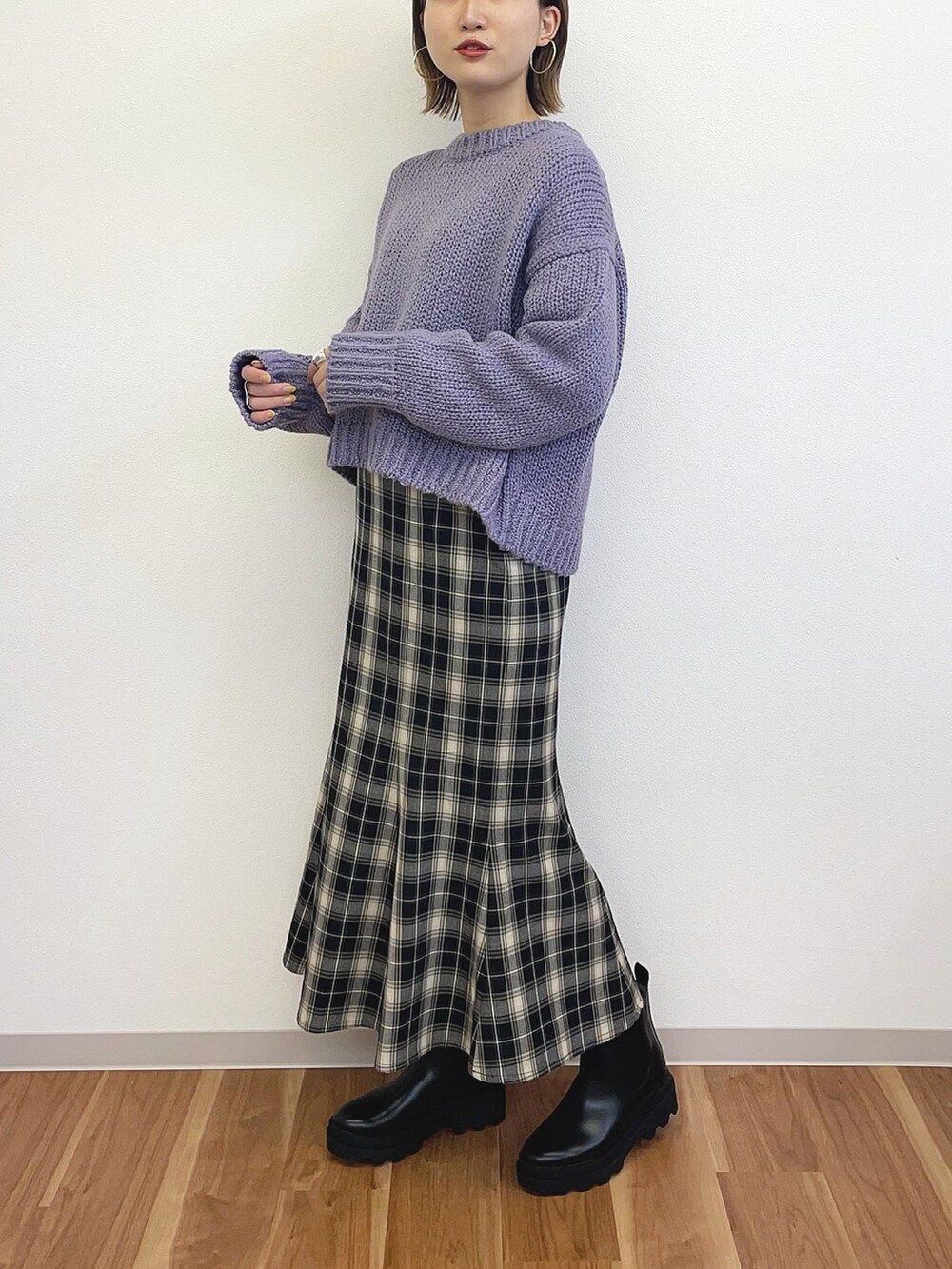 パープル系のニット/セーター、ブラック系のスカート、ブラック系のブーツを着用したレディースの冬コーディネートの2枚目の写真