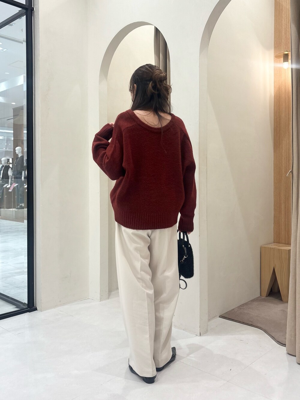 レッド系のニット/セーター、ホワイト系のその他パンツ、ブラック系のショルダーバッグを着用したレディースの秋コーディネートの2枚目の写真
