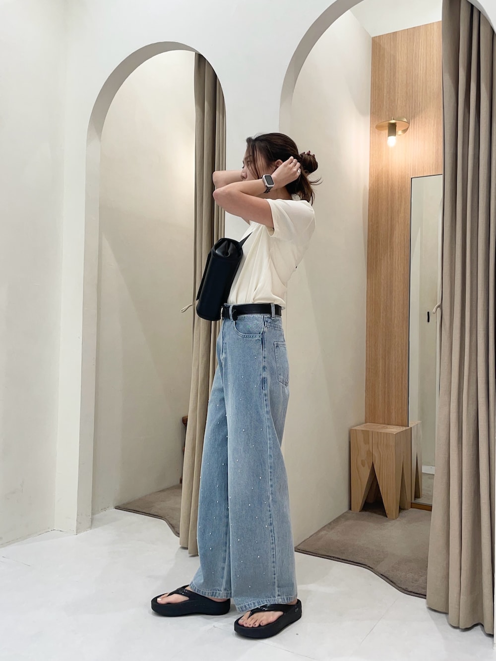 ブルー系のデニムパンツ、ベージュ系のTシャツ/カットソー、ブラック系のショルダーバッグを着用したレディースの夏コーディネートの4枚目の写真