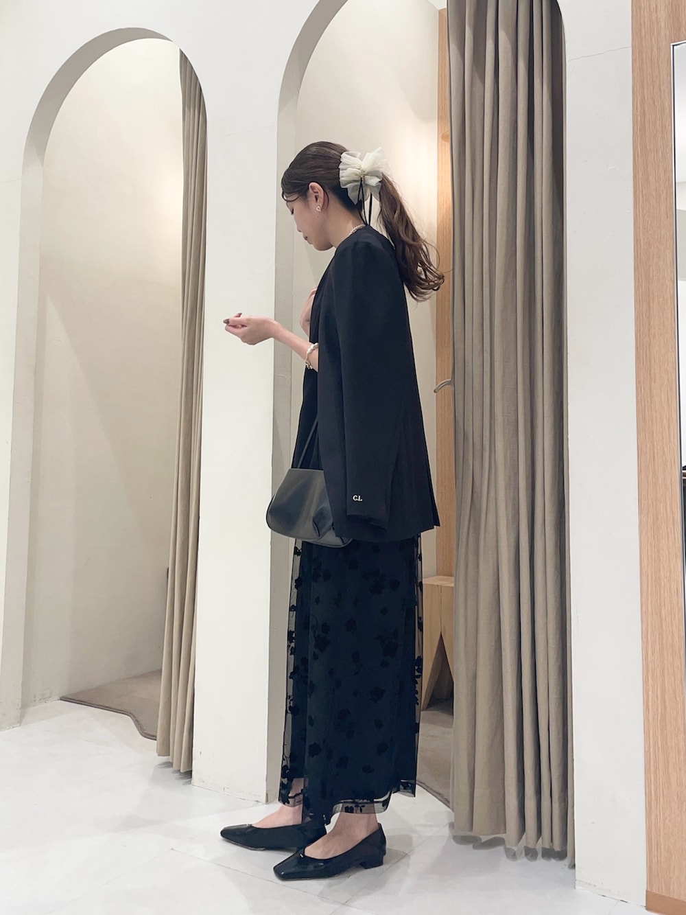 ブラック系のテーラードジャケット、ブラック系のワンピース、ブラック系のショルダーバッグを着用したレディースの春コーディネートの3枚目の写真