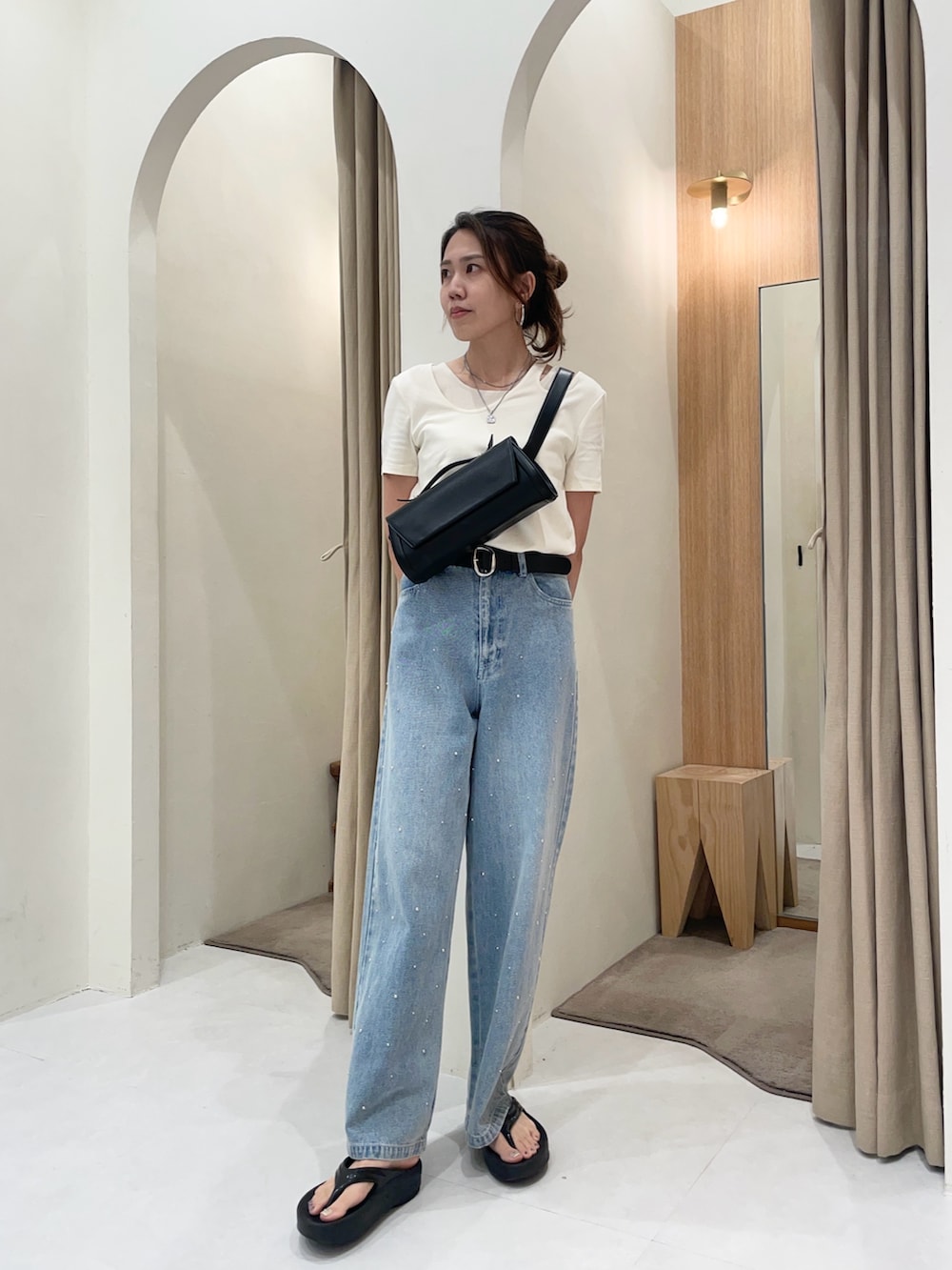 ブルー系のデニムパンツ、ベージュ系のTシャツ/カットソー、ブラック系のショルダーバッグを着用したレディースの夏コーディネートの3枚目の写真