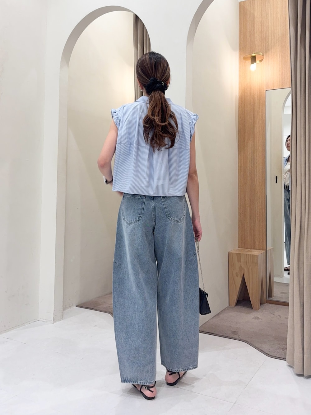 ブルー系のシャツ/ブラウス、ブルー系のデニムパンツ、ブラック系のショルダーバッグを着用したレディースの夏コーディネートの4枚目の写真