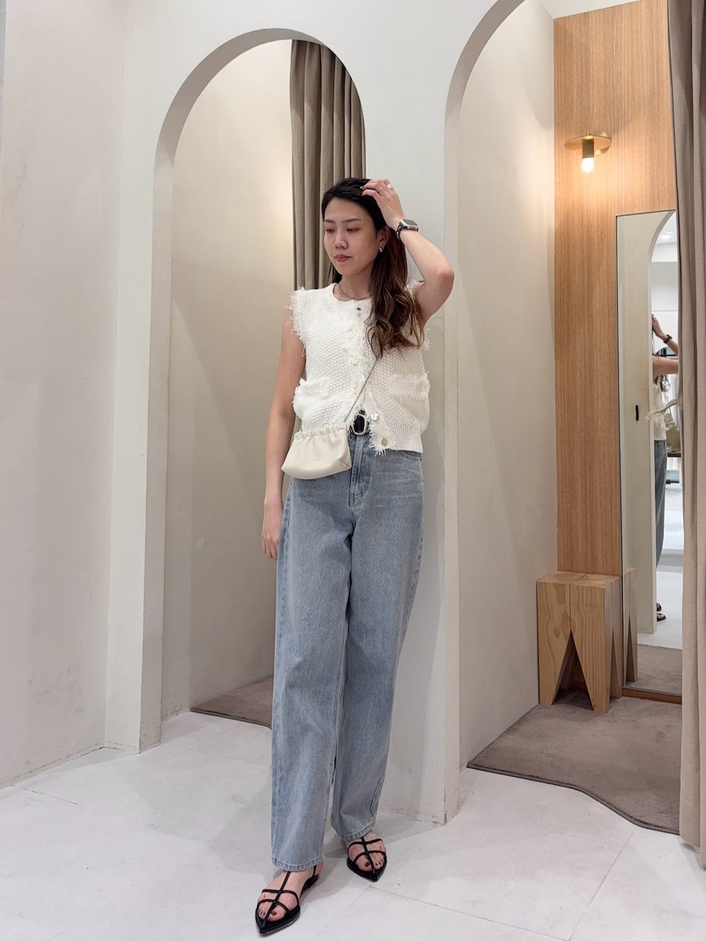 ホワイト系のニット/セーター、ホワイト系のショルダーバッグ、ブルー系のデニムパンツを着用したレディースの春コーディネートの3枚目の写真