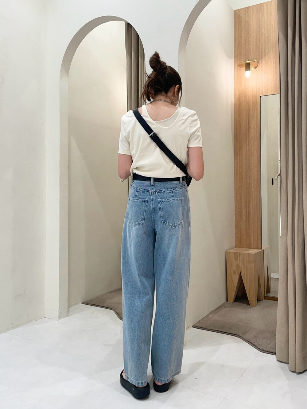 ブルー系のデニムパンツ、ベージュ系のTシャツ/カットソー、ブラック系のショルダーバッグを着用したレディースの夏コーディネートの2枚目の写真