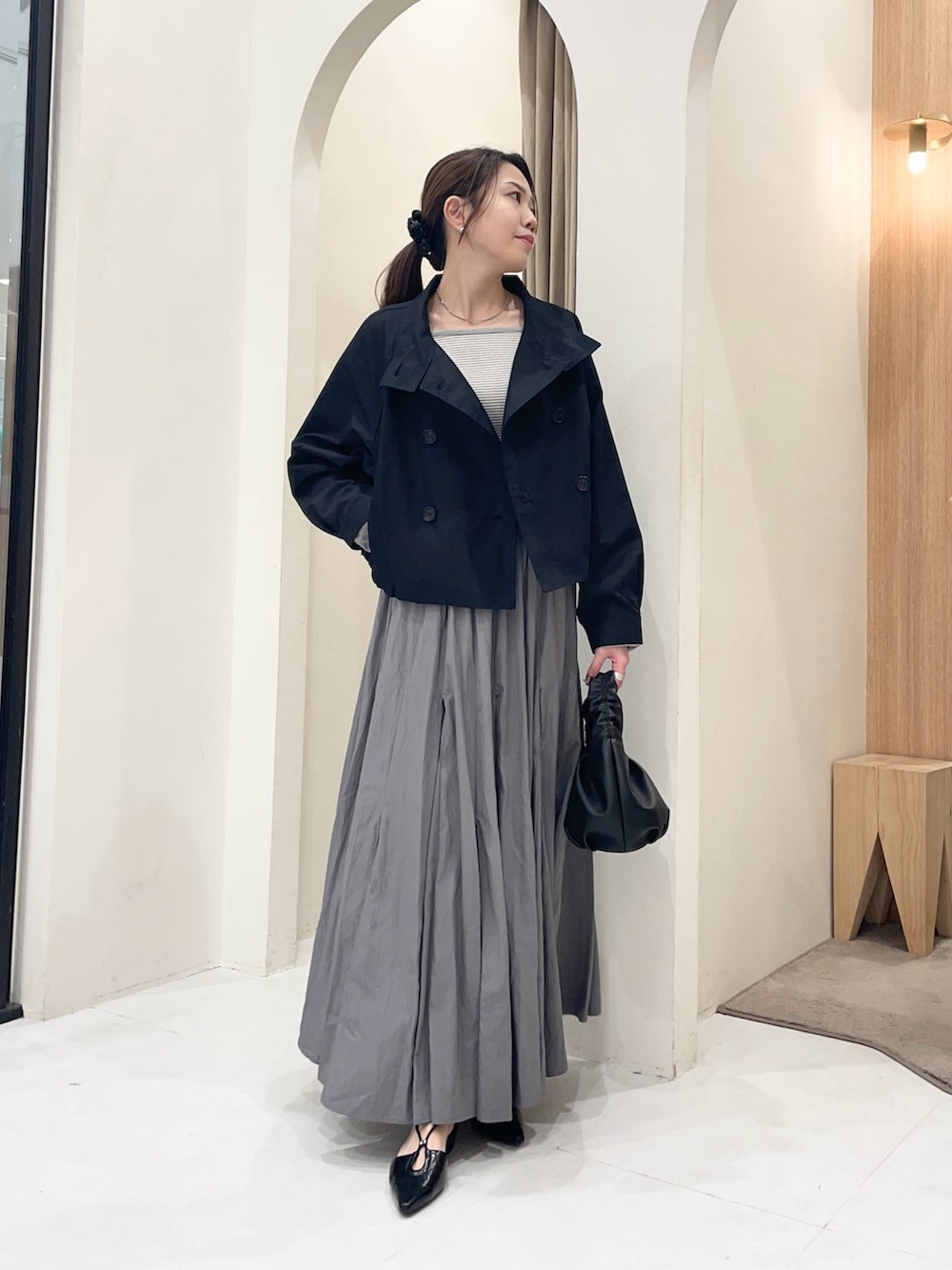 ブラック系のトレンチコート、グレー系のTシャツ/カットソー、グレー系のスカートを着用したレディースの春コーディネートの5枚目の写真