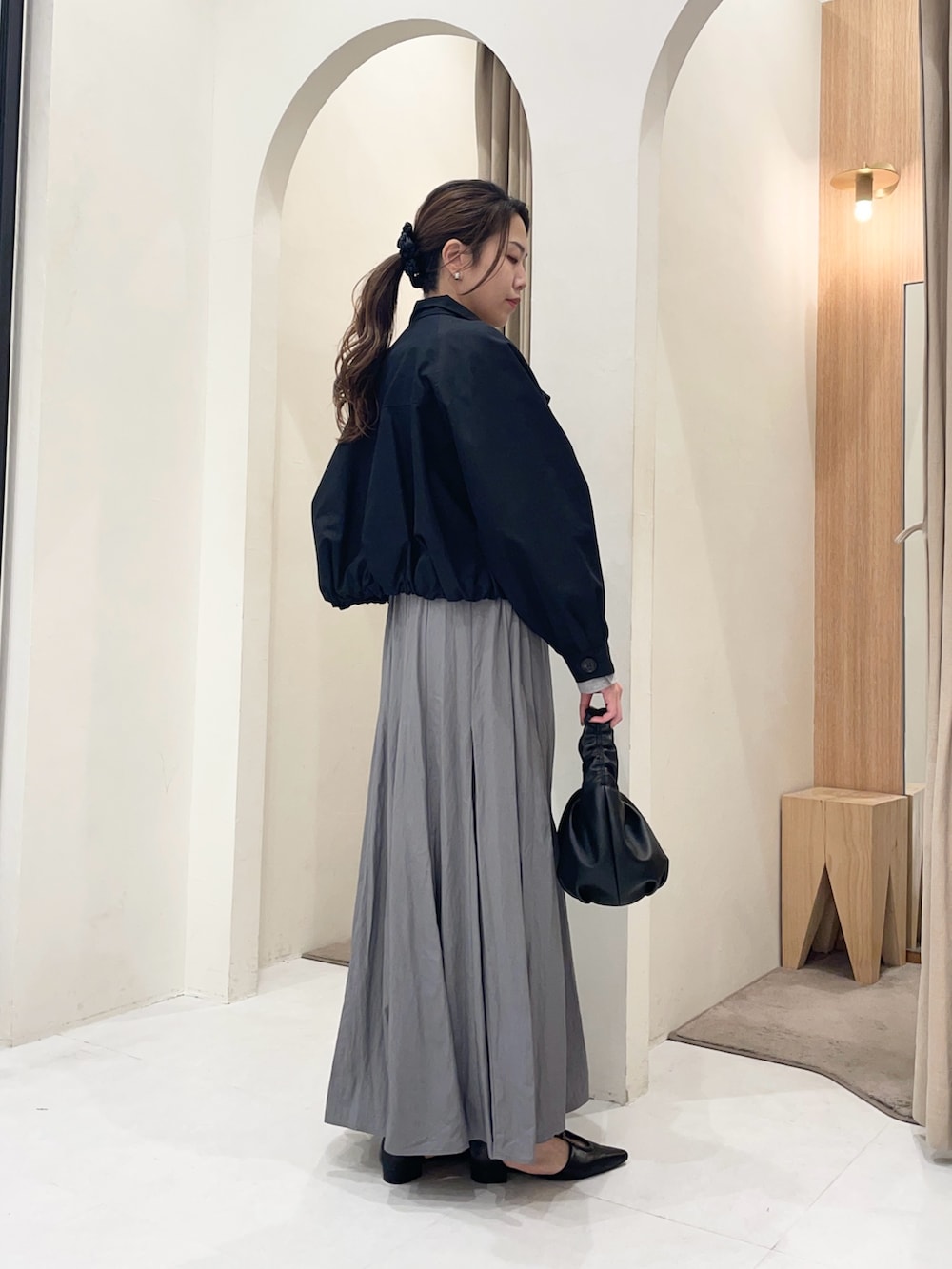 ブラック系のトレンチコート、グレー系のTシャツ/カットソー、グレー系のスカートを着用したレディースの春コーディネートの3枚目の写真