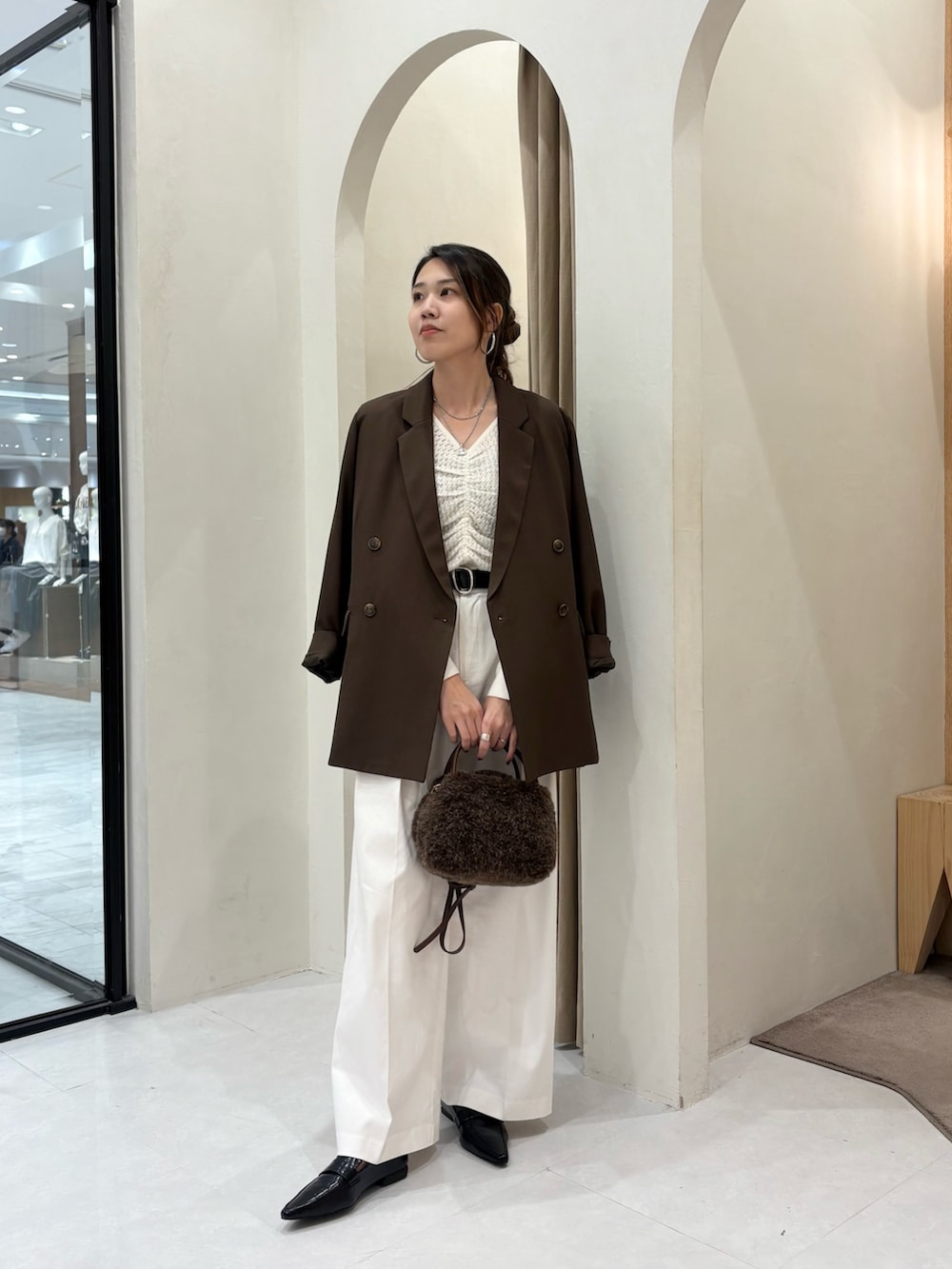 ホワイト系のニット/セーター、ブラウン系のテーラードジャケット、ブラウン系のボストンバッグを着用したレディースの秋コーディネートの4枚目の写真
