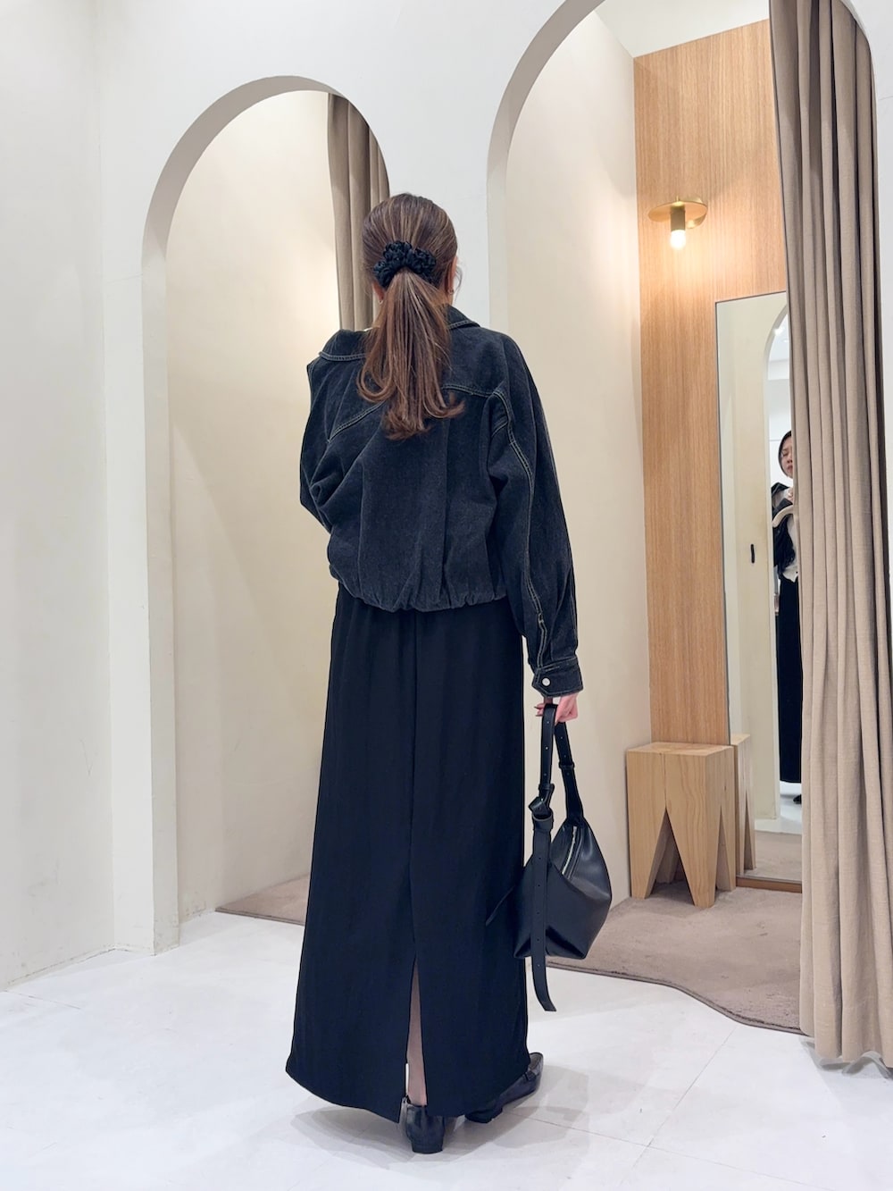 ブラック系のブルゾン、ホワイト系のカーディガン/ボレロ、ブラック系のスカートを着用したレディースの春コーディネートの2枚目の写真