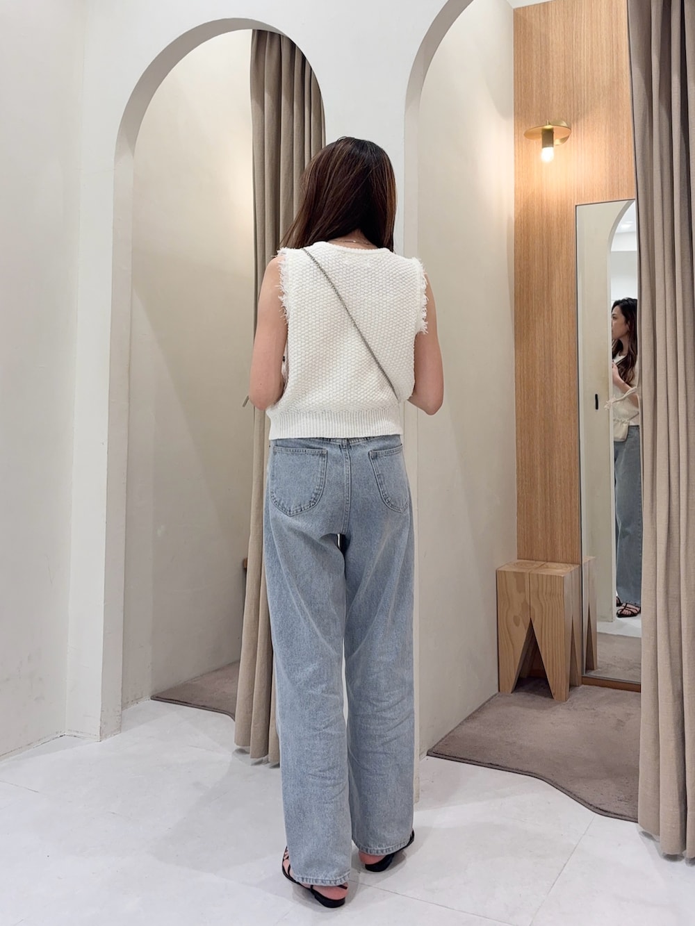 ホワイト系のニット/セーター、ホワイト系のショルダーバッグ、ブルー系のデニムパンツを着用したレディースの春コーディネートの2枚目の写真