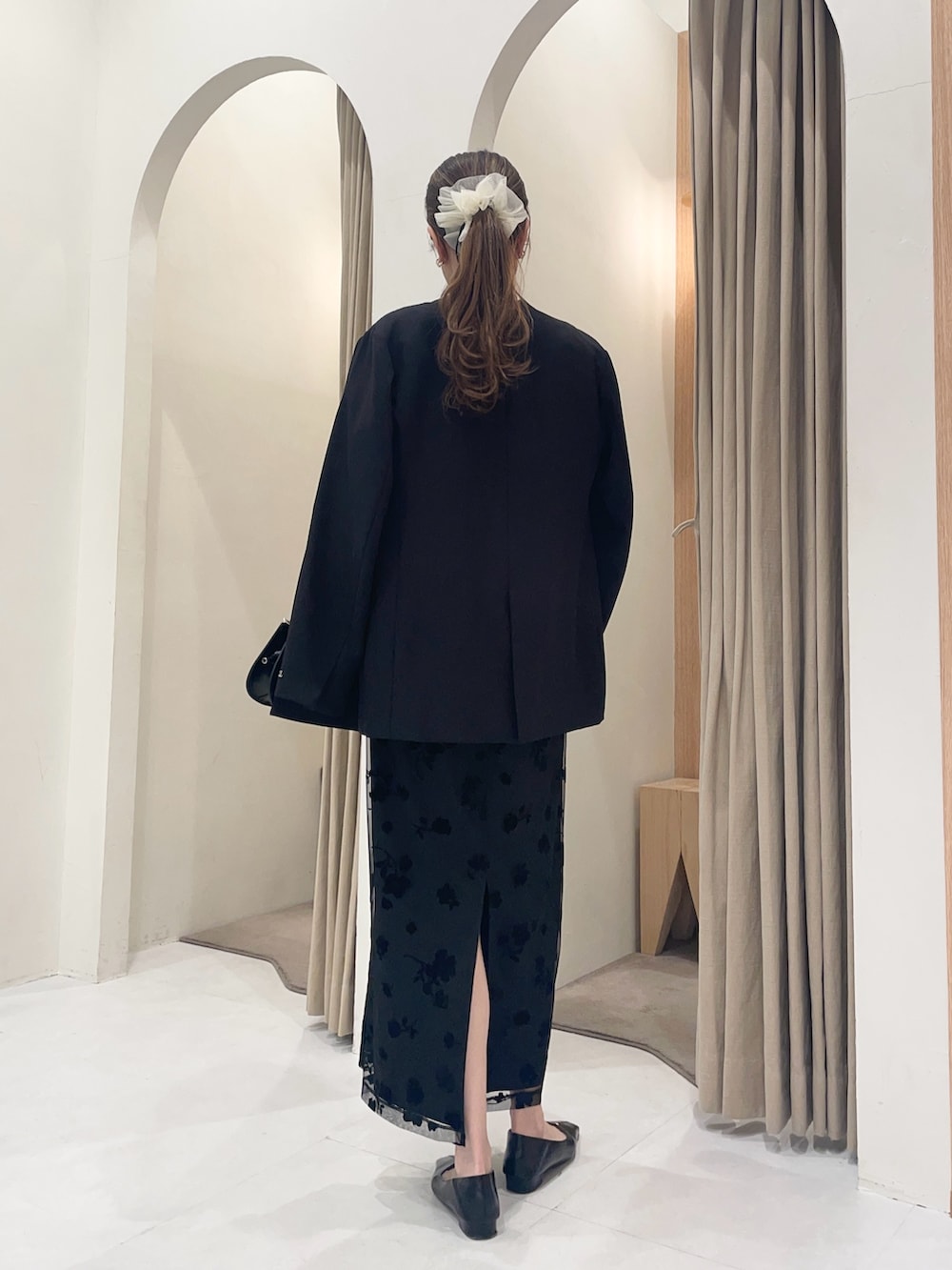 ブラック系のテーラードジャケット、ブラック系のワンピース、ブラック系のショルダーバッグを着用したレディースの春コーディネートの2枚目の写真