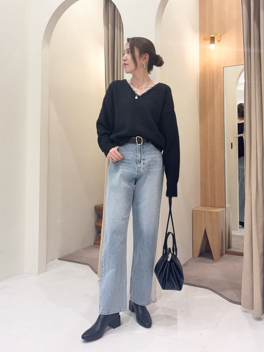 ブラック系のニット/セーター、ブルー系のデニムパンツ、ブラック系のショルダーバッグを着用したレディースの冬コーディネートの3枚目の写真