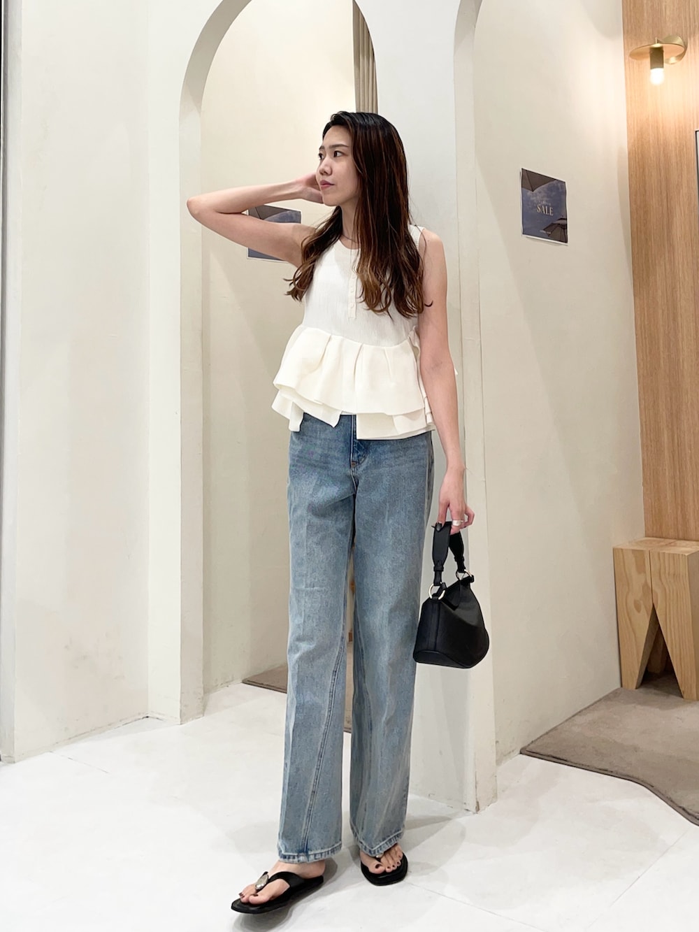 ホワイト系のニット/セーター、ブルー系のデニムパンツ、ブラック系のショルダーバッグを着用したレディースの夏コーディネートの4枚目の写真