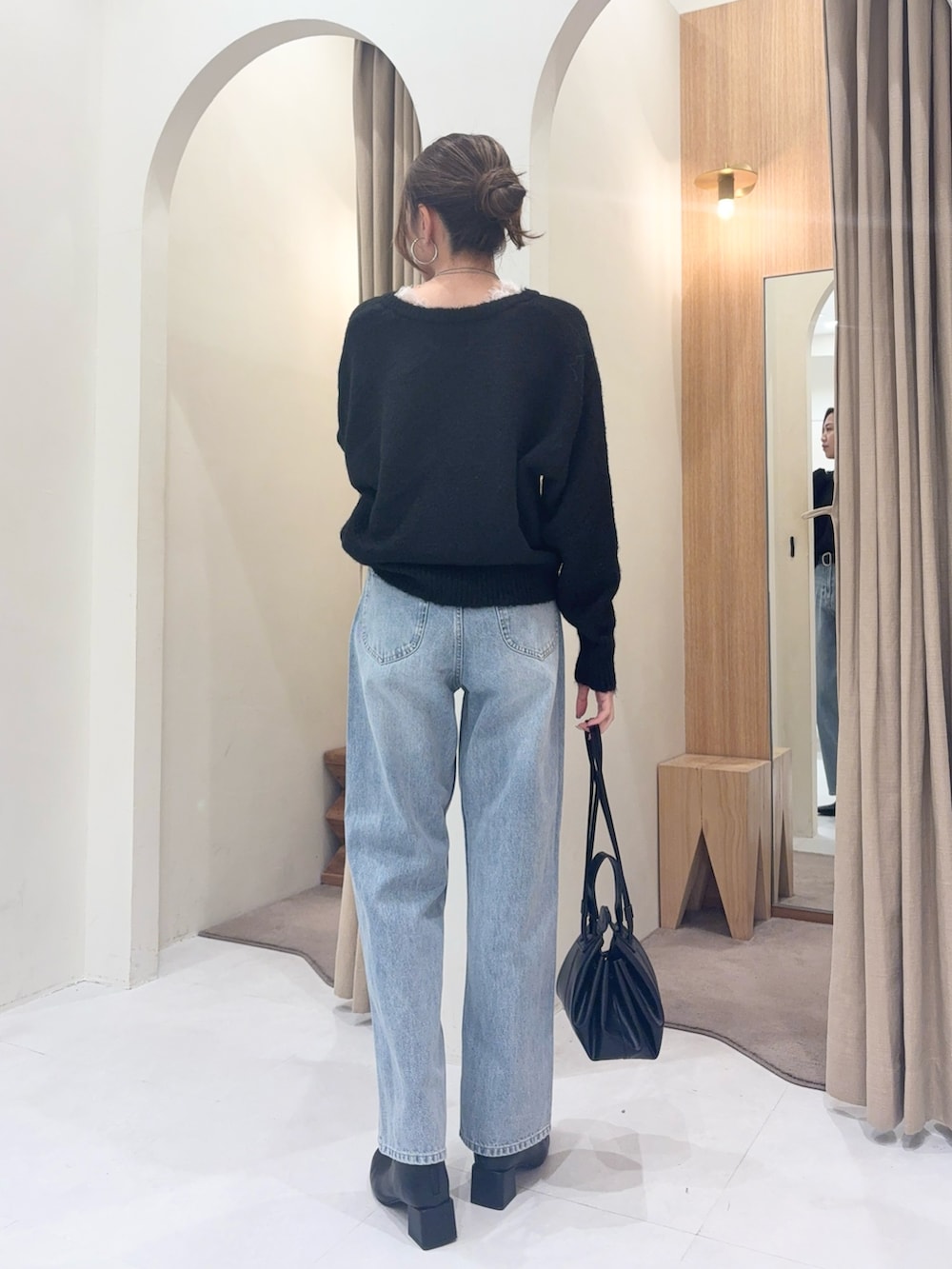 ブラック系のニット/セーター、ブルー系のデニムパンツ、ブラック系のショルダーバッグを着用したレディースの冬コーディネートの2枚目の写真