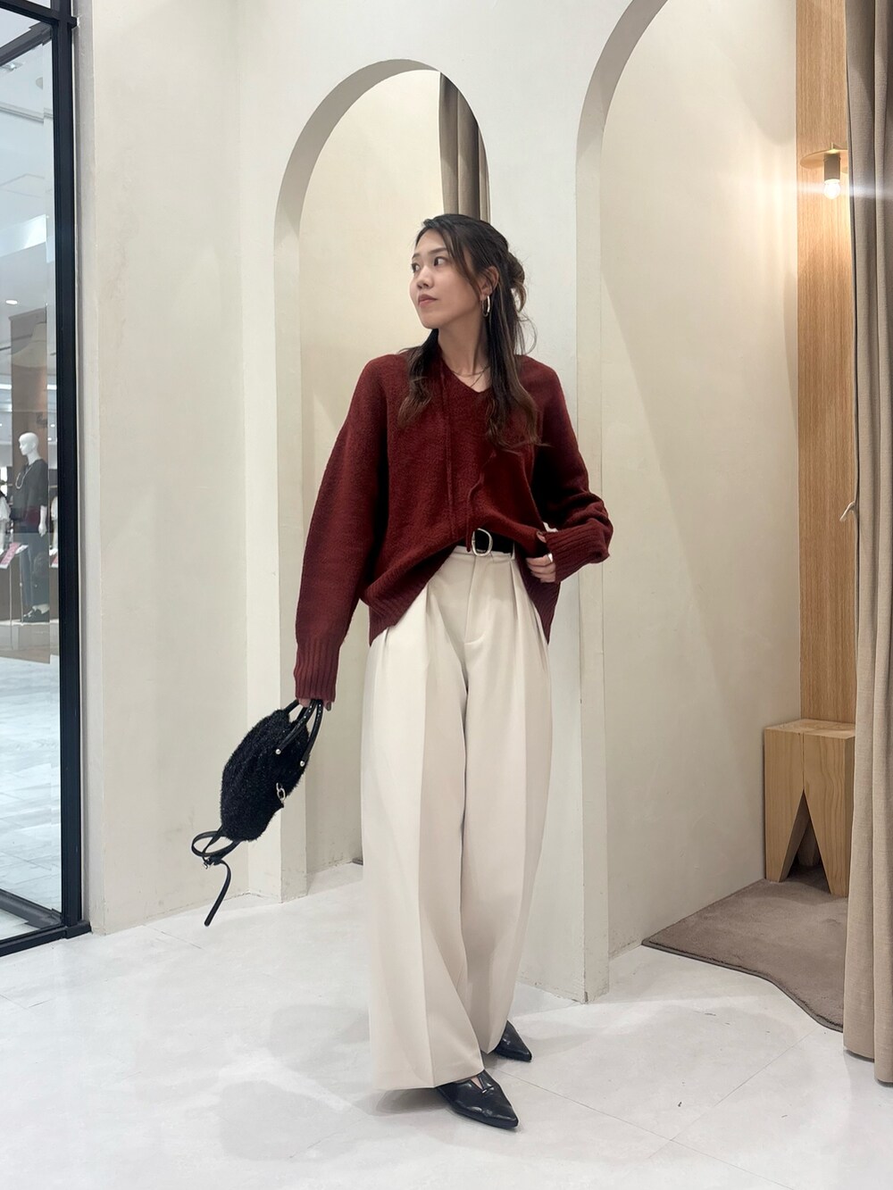 レッド系のニット/セーター、ホワイト系のその他パンツ、ブラック系のショルダーバッグを着用したレディースの秋コーディネートの3枚目の写真
