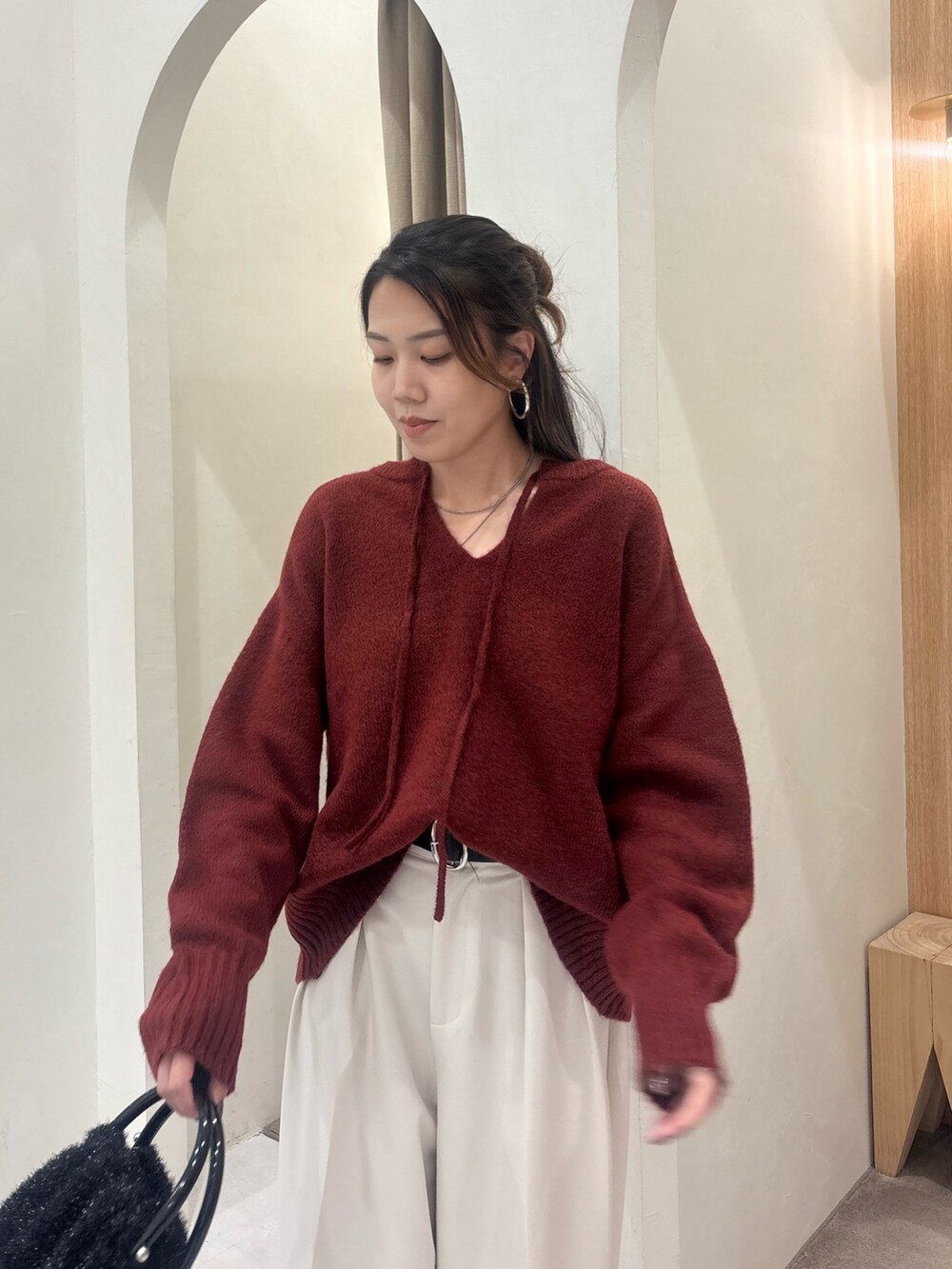 レッド系のニット/セーター、ホワイト系のその他パンツ、ブラック系のショルダーバッグを着用したレディースの秋コーディネートの4枚目の写真